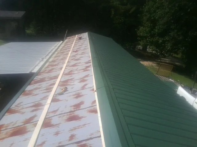 Old rusted panels beside newly installed green metal roofing — Wind Damage Roof Repair by Roofing Brothers in North Bend